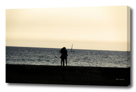 Silhouette of an embracing couple looking at the sea