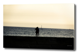 Silhouette of an embracing couple looking at the sea
