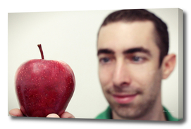 Man looking at red apple that placed on his hand