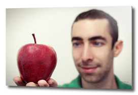 Man looking at red apple that placed on his hand