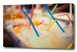 Selection of plastic cups with juice and colored straws