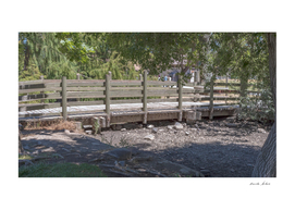Rustic bridge with wooden fence over a dry stream near lake