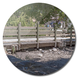 Rustic bridge with wooden fence over a dry stream near lake