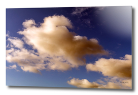 Dramatic Reddish Brown and white fluffy clouds in blue sky