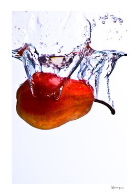 Pear falls into water with a splash on white background