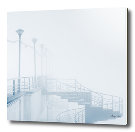Lantern in fog with spiral staircase on pier